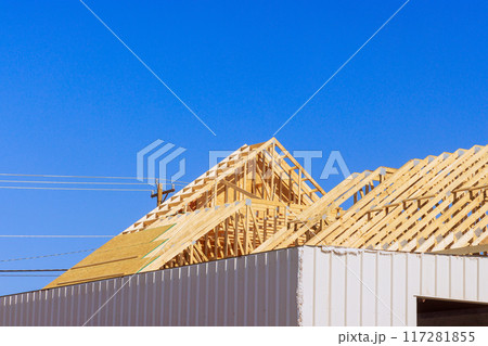 Frame installation of wooden roofing trusses to house under construction 117281855