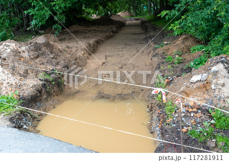 Excavation work on a pathway collecting water after rainfall 117281911