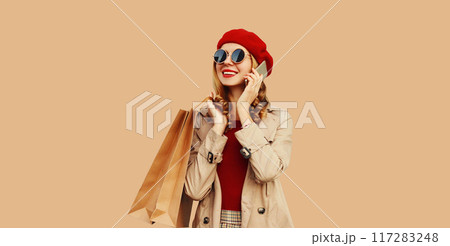Autumn portrait of happy smiling young woman with shopping bag calling on mobile phone Autumn portrait of happy smiling young woman with shopping bag calling on mobile phone 117283248