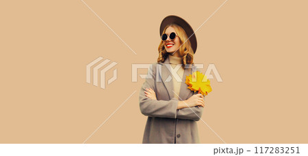 Autumn color style outfit, portrait of beautiful smiling young woman with yellow maple leaves 117283251
