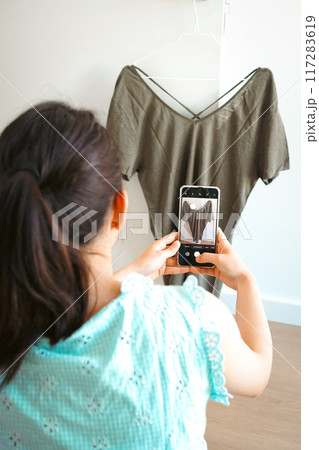 ネット販売するために古着の写真を撮る若い女性の後ろ姿 ネット販売するために古着の写真を撮る若い女性の後ろ姿 117283619