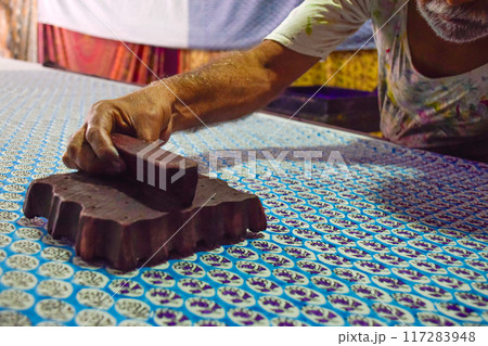Artisan hand stamping patterns in ink with block on traditional Indian textiles Artisan hand stamping patterns in ink with block on traditional Indian textiles 117283948
