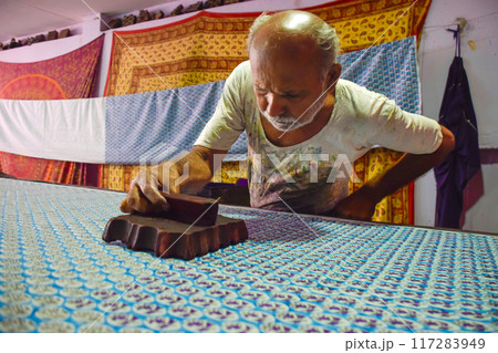 Artisan stamping patterns in ink on traditional Indian textiles as colorful sari 117283949