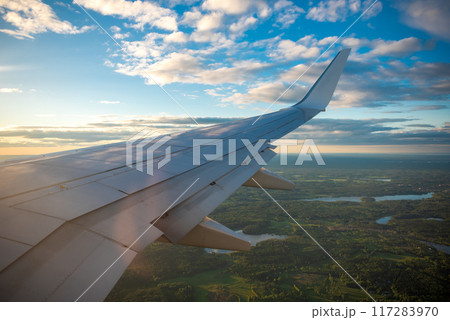 Aircraft flying in sunset. Clouds, rainbow and a wing of airbus from the airplane window Aircraft flying in sunset. Clouds, rainbow and a wing of airbus from the airplane window 117283970
