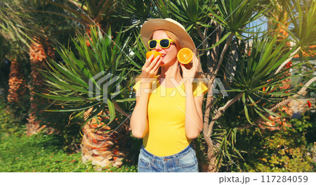 Summer, vacation, happy cheerful young woman with slices of orange fruits on beach with palm 117284059