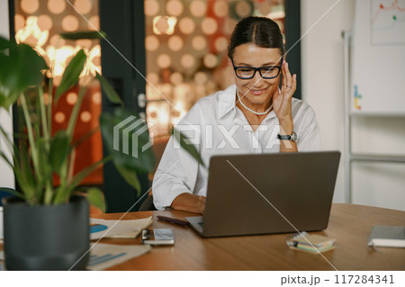 A Dedicated and Focused Professional Working Intently on a Laptop in a Modern Office Space 117284341