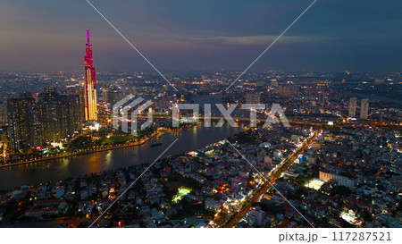 An aerial view of Ho Chi Minh City at sunset, vibrant colorful sky, the illuminated Landmark 81 skyscraper, the reflecting Saigon River in city lights of dynamic urban, awe cityscape 117287521