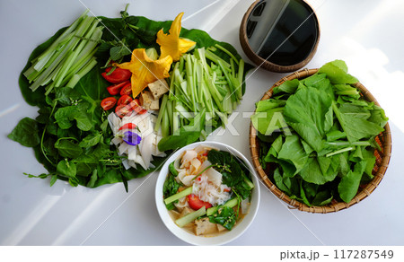 vibrant Vietnamese meal on green leaf with fresd raw material as sliced tomatoes, squash blossoms, lemongrass, vegetable for healthy vegan food 117287549