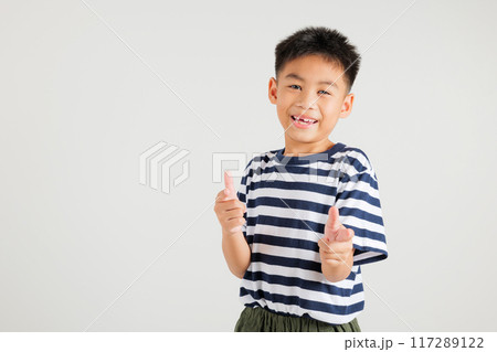 Cheerful Asian young kid boy excitedly makes two gun finger gesture to the camera with a friendly and cheeky expression. Isolated on white background, primary child exudes positivity and joy 117289122
