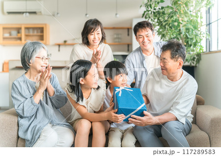 家のソファで家族団欒する三世代家族・ファミリー（誕生日・敬老の日） 117289583