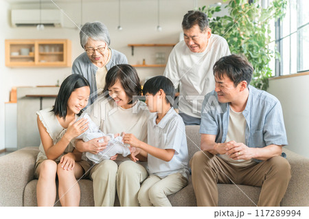 家のソファで赤ちゃんを抱っこするママと三世代家族・ファミリー 117289994