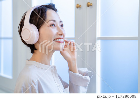 ヘッドフォンで音楽を聴くミドルの女性 117290009