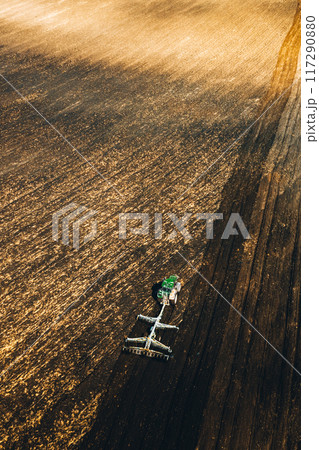 Aerial View. Tractor Plowing Field In Spring Season. Beginning Of Agricultural Spring Season. Cultivator Pulled By A Tractor In Countryside Rural Field Landscape 117290880