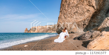 Woman beach white dress flying on Wind. Summer Vacation. A happy woman takes vacation photos to send to friends. Woman beach white dress flying on Wind. Summer Vacation. A happy woman takes vacation photos to send to friends. 117291377