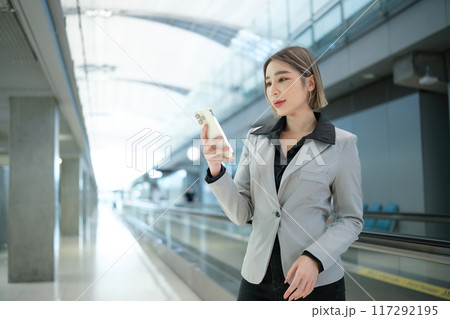 A woman in a business suit is looking at her cell phone in a large 117292195