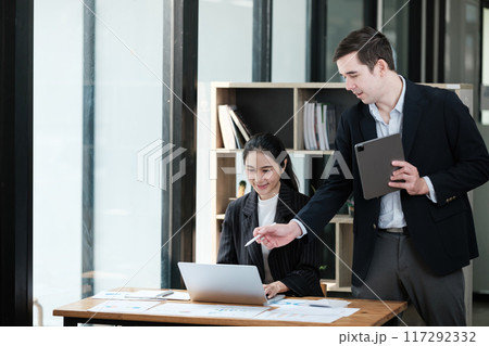 A man and a woman are working together at a desk 117292332