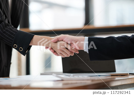Two people shaking hands in a business setting 117292341