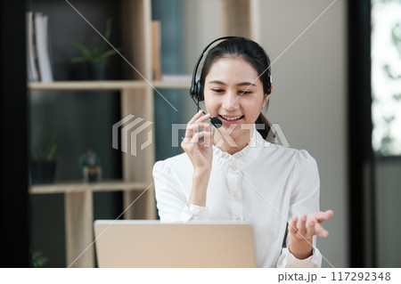 A woman wearing a headset is talking on a phone A woman wearing a headset is talking on a phone 117292348