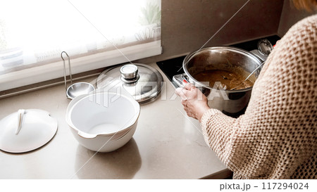 Woman plating meat with sauce in a kitchen Woman plating meat with sauce in a kitchen 117294024