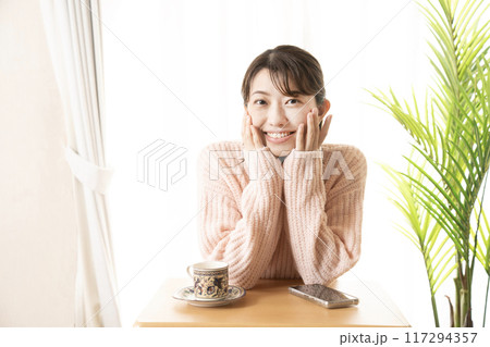 カフェでほおづえをついて微笑む女性 117294357