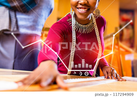 A woman is sitting at a table with a computer screen in front of her 117294909