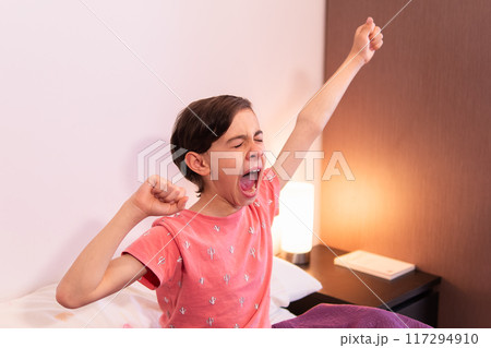 Young child stretching arms in bed after waking up 117294910