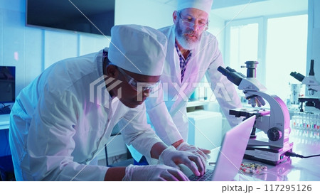 Two chemists work meticulously at a high-tech laboratory, analyzing data while using advanced equipment to advance their research in medicine and technology. Two chemists work meticulously at a high-tech laboratory, analyzing data while using advanced equipment to advance their research in medicine and technology. 117295126