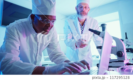 Two chemists work meticulously at a high-tech laboratory, analyzing data while using advanced equipment to advance their research in medicine and technology. Two chemists work meticulously at a high-tech laboratory, analyzing data while using advanced equipment to advance their research in medicine and technology. 117295128
