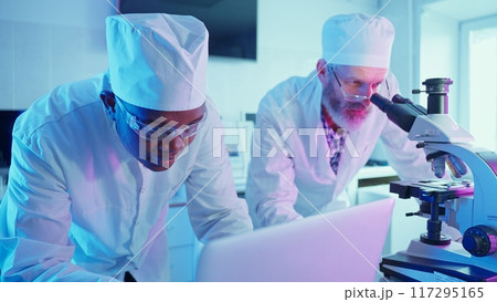 Two chemists work meticulously at a high-tech laboratory, analyzing data while using advanced equipment to advance their research in medicine and technology. 117295165