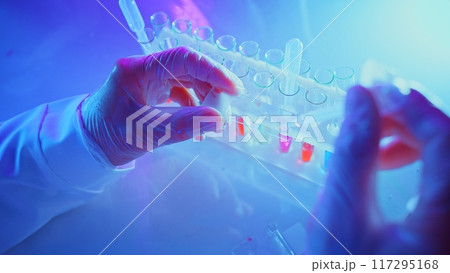 Researchers in a laboratory conduct innovative chemical analysis using advanced equipment and vibrant purple lighting. 117295168