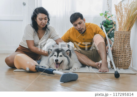 Asian couple with prosthetic leg sitting in living room Asian couple with prosthetic leg sitting in living room 117295814