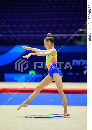 A young gymnast displays dedication, determination, and grace with a hoop in a lively competition A young gymnast displays dedication, determination, and grace with a hoop in a lively competition 117296020