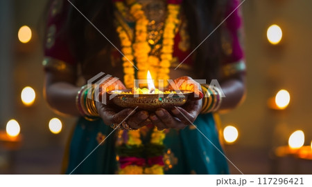 Traditional Indian Diya Lamp in Woman's Hands during Diwali Festival 117296421