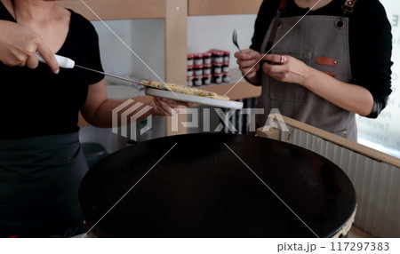 Putting crepe on dish for service. Putting crepe on dish for service. 117297383