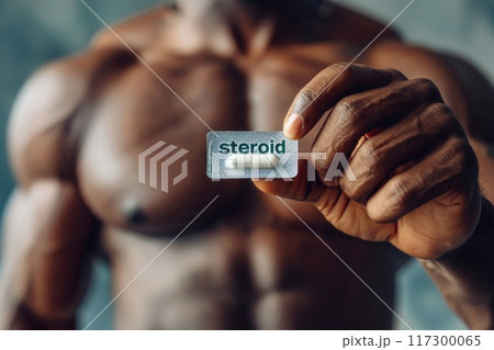 Man with an athletic physique holding steroids - portrayal of the potential risks and ethical considerations surrounding performance-enhancing substances in sports and fitness culture. 117300065