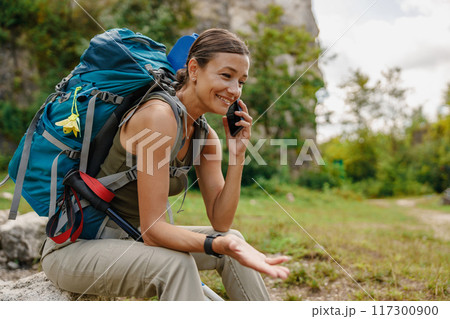A hiker is taking a phone call while enjoying a beautiful outdoor adventure in nature 117300900