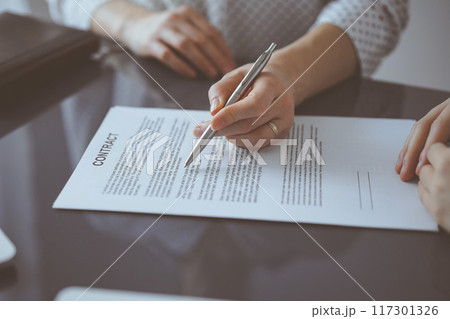 Business people sitting and discussing contract in office, closeup. Partners or lawyers working together at meeting. Teamwork and partnership 117301326
