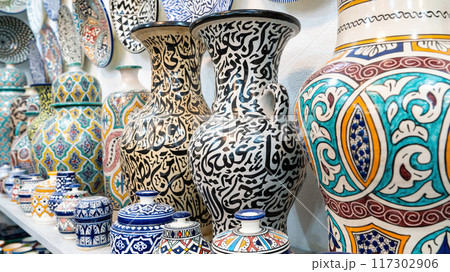 Colorful Moroccan pottery and ceramics displayed outside shops in the souks, showcasing traditional designs and craftsmanship. Colorful Moroccan pottery and ceramics displayed outside shops in the souks, showcasing traditional designs and craftsmanship. 117302906