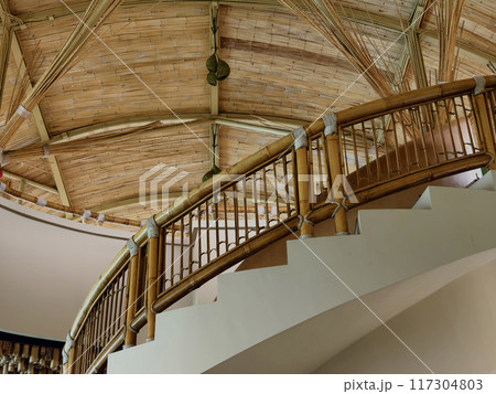 There is a spiral staircase in a building with a wooden railing 117304803
