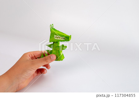 Handheld green paper crocodile craft, Made from recycled paper, colored with markers or paint. Showcasing playful ingenuity and creative artwork 117304855