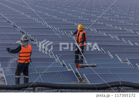 Worker Cleaning floating solar panels or solar cell Platform system on the lake with brush and water 117305172