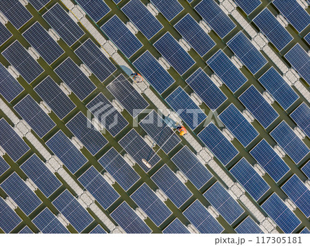 Worker Cleaning floating solar panels or solar cell Platform system on the lake with brush and water 117305181