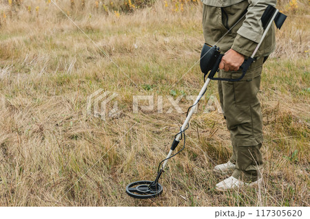 Man with electronic metal detector device working on outdoors. Man with electronic metal detector device working on outdoors. 117305620