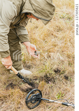 Man with electronic metal detector device working on outdoors. Man with electronic metal detector device working on outdoors. 117305621