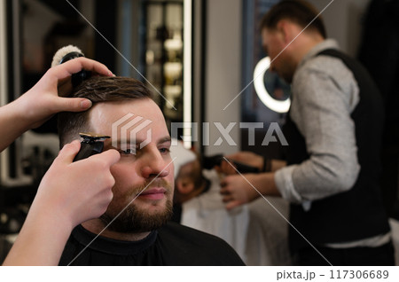 Haircut alignment of the contour of the head with trimmer. Short haircut in the barbershop. Haircut alignment of the contour of the head with trimmer. Short haircut in the barbershop. 117306689