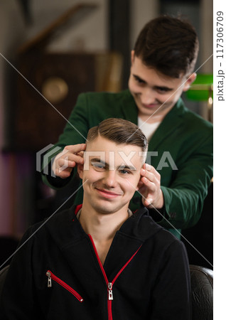 Barber shows the final result of the haircut to the client 117306709