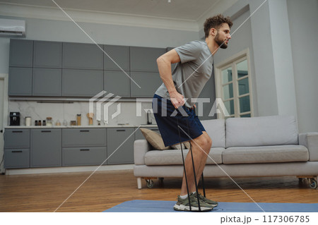 Training to become the best. Beautiful young man in sports clothing exercising at home. Training to become the best. Beautiful young man in sports clothing exercising at home. 117306785