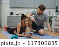 Training to become the best. Beautiful young woman and man in sports clothing exercising at home. 117306835