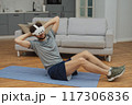 Training to become the best. Beautiful young man in sports clothing exercising at home. 117306836