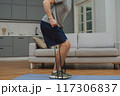 Training to become the best. Beautiful young man in sports clothing exercising at home. 117306837